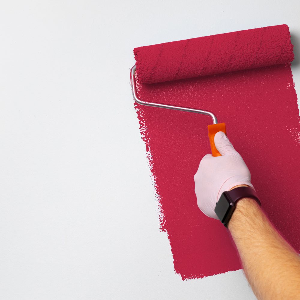 Gloved male hand painting wall into classic blue color
