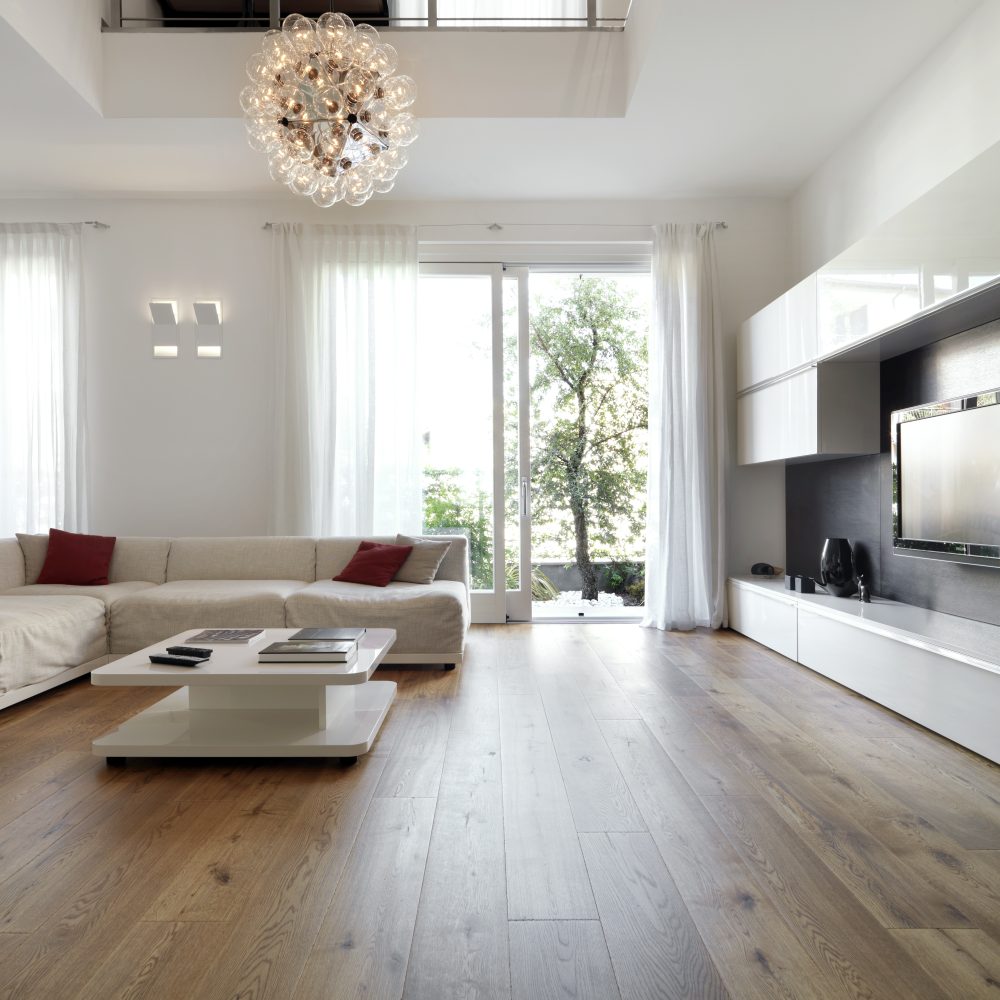 interiors of a modern living room whose wooden floor overlooks the garden in the foreground on the left the fabric sofa with a coffee table, in front of it the tv furniture