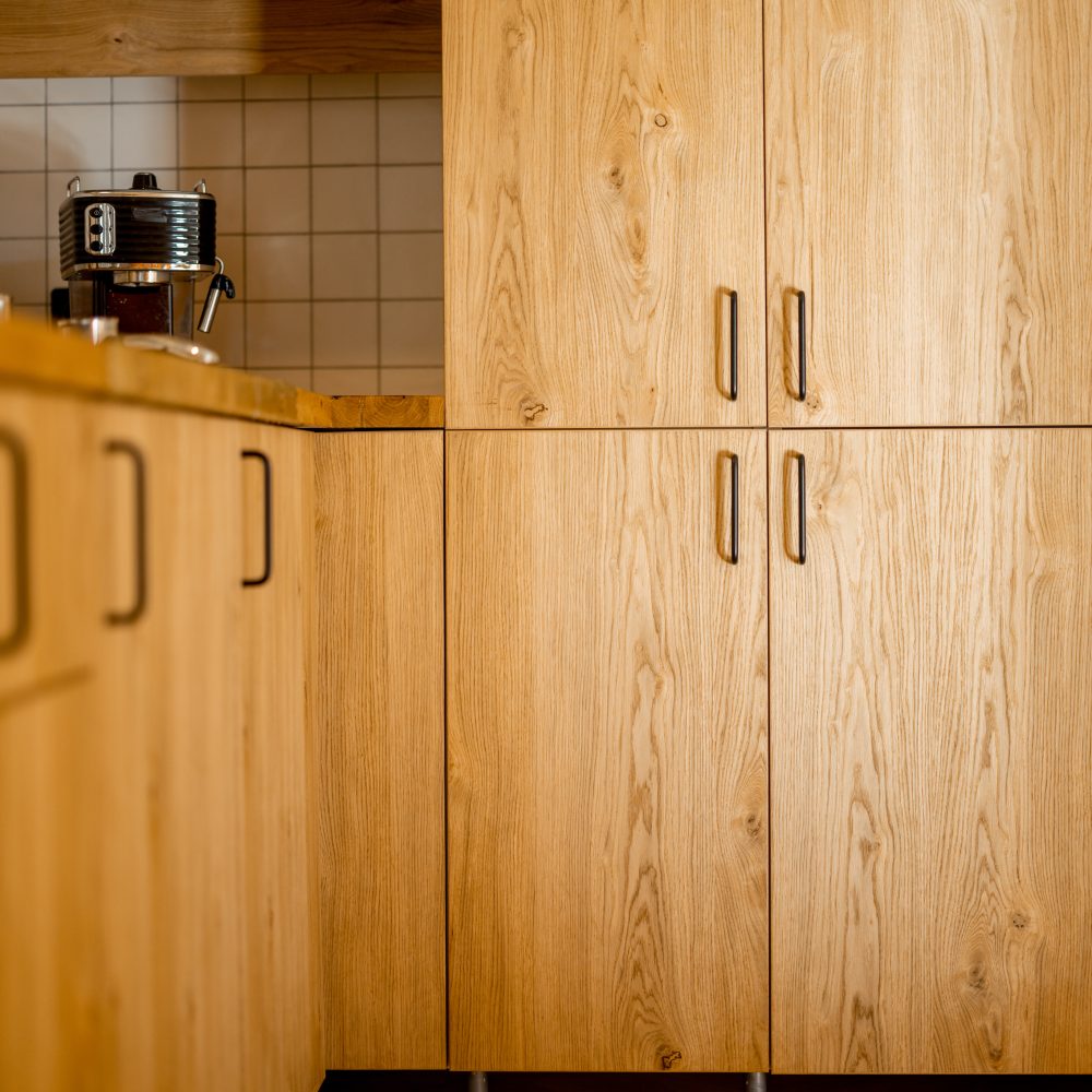 Close-up of kitchen facades made of oak veneer with black hadles