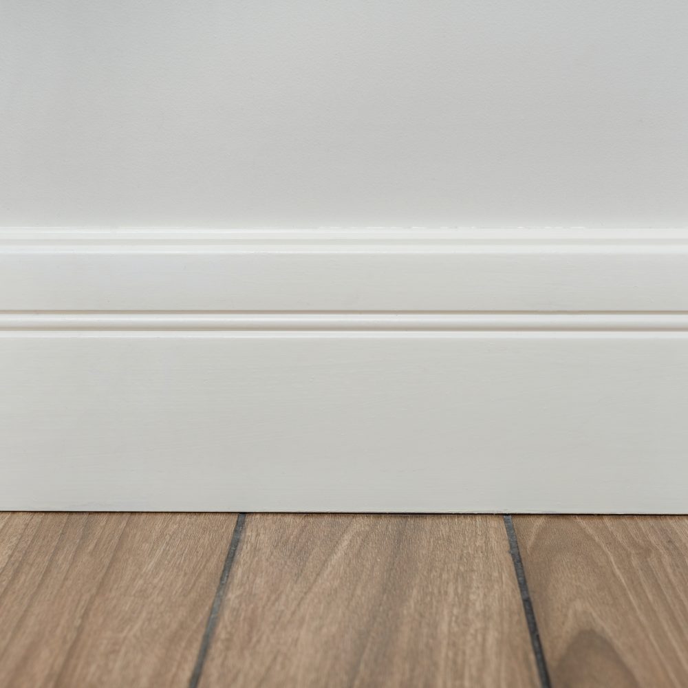 Interior concept. Light matte wall, white baseboard and tiles immitating hardwood flooring