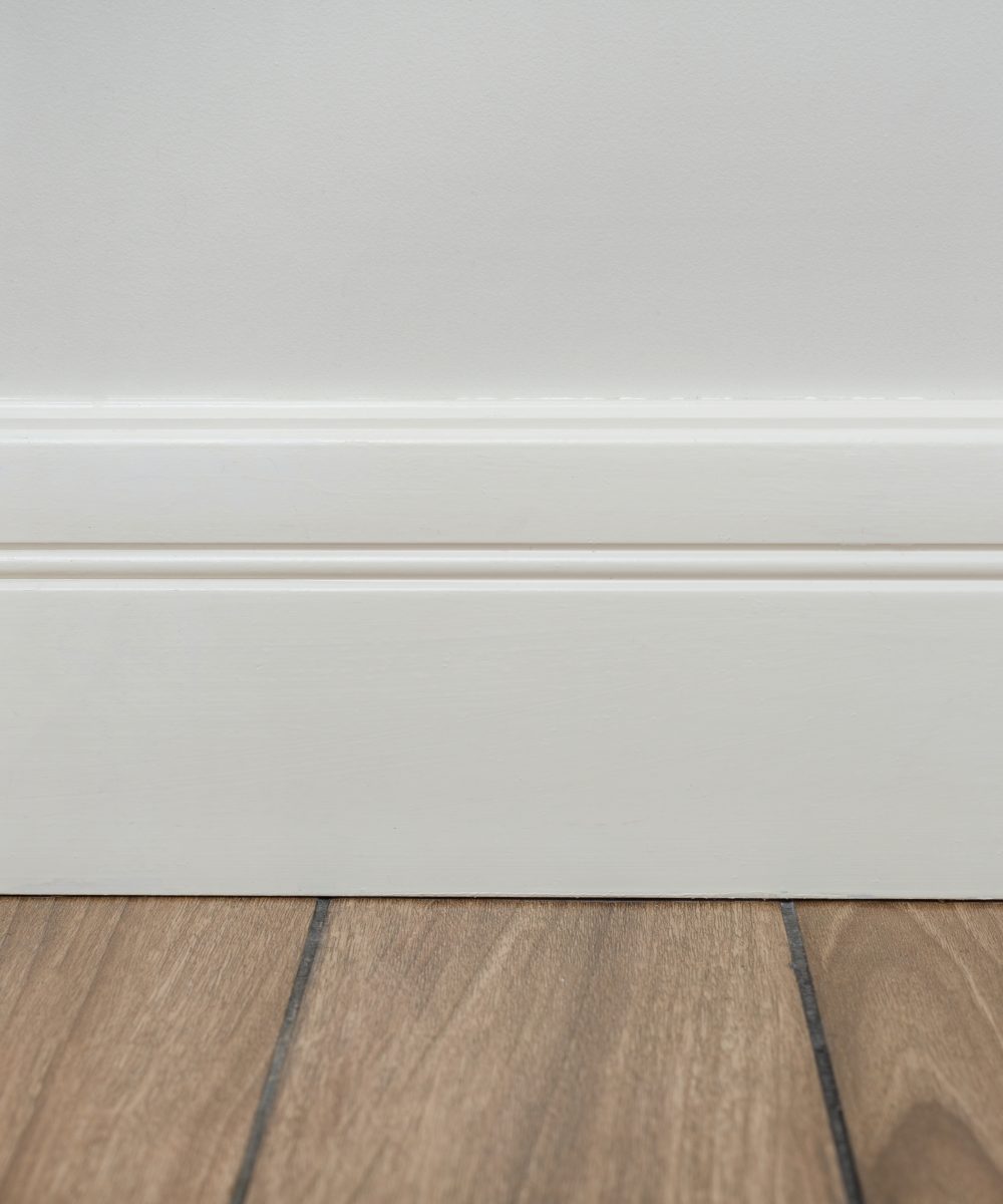 Interior concept. Light matte wall, white baseboard and tiles immitating hardwood flooring
